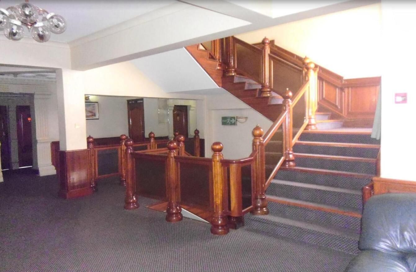 A grand staircase with wooden balusters and a carpeted floor.