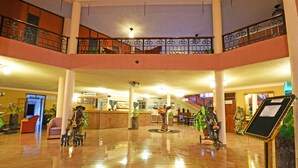 A spacious lobby with a reception desk, seating area, and a staircase leading to an upper level. - Imperial Golf View Hotel (Entebbe)