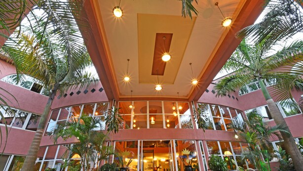 A hotel with a curved facade, large windows, and a central entrance. - Imperial Golf View Hotel (Entebbe)