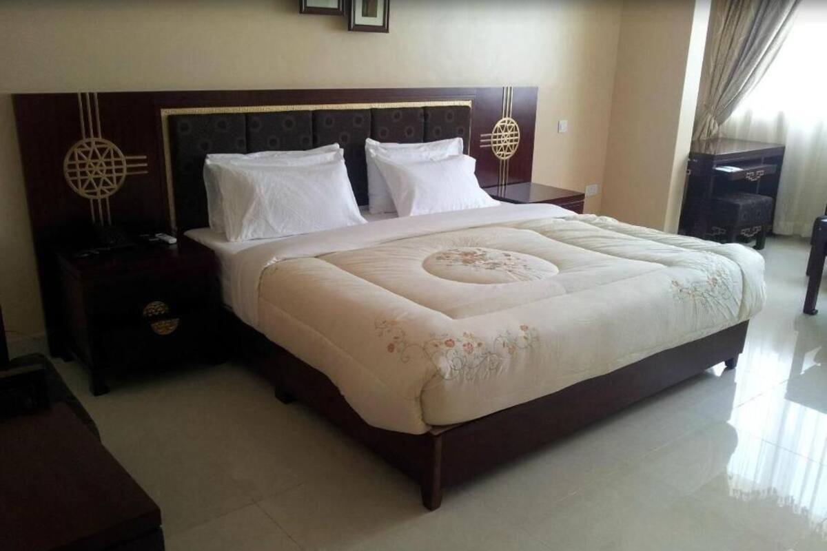 A large bed with a floral bedspread, two bedside tables with lamps, and a decorative wall piece.