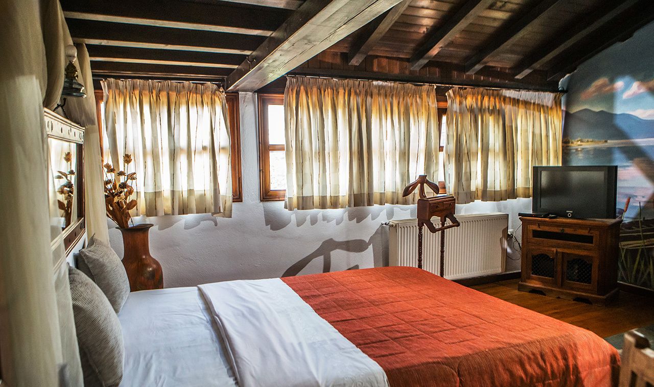A cozy room with a bed, a television, and a window with curtains.