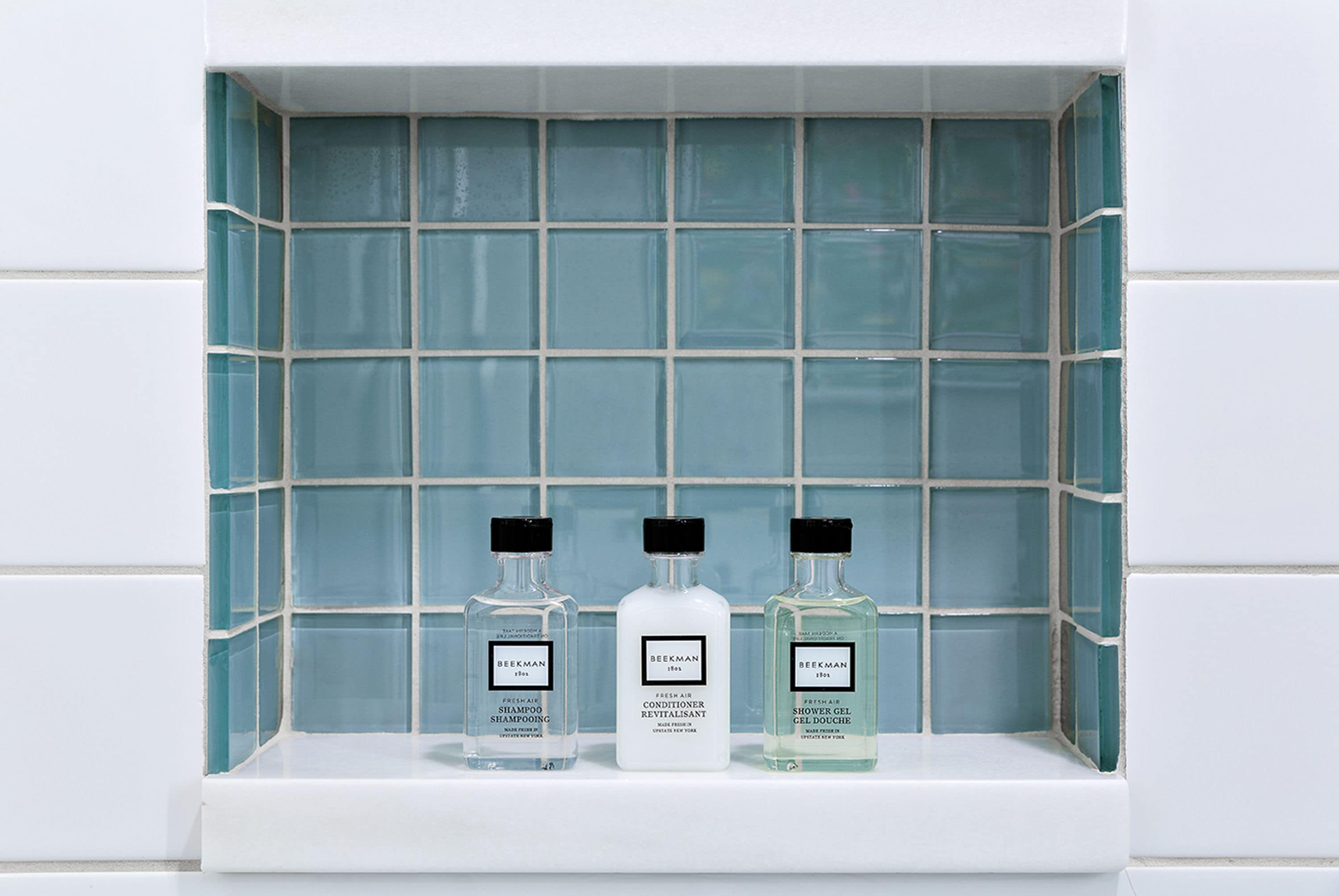 Three bottles of Beekman products on a shelf against a tiled wall.