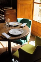 A dining table set with plates, glasses, and a folded napkin, surrounded by chairs.