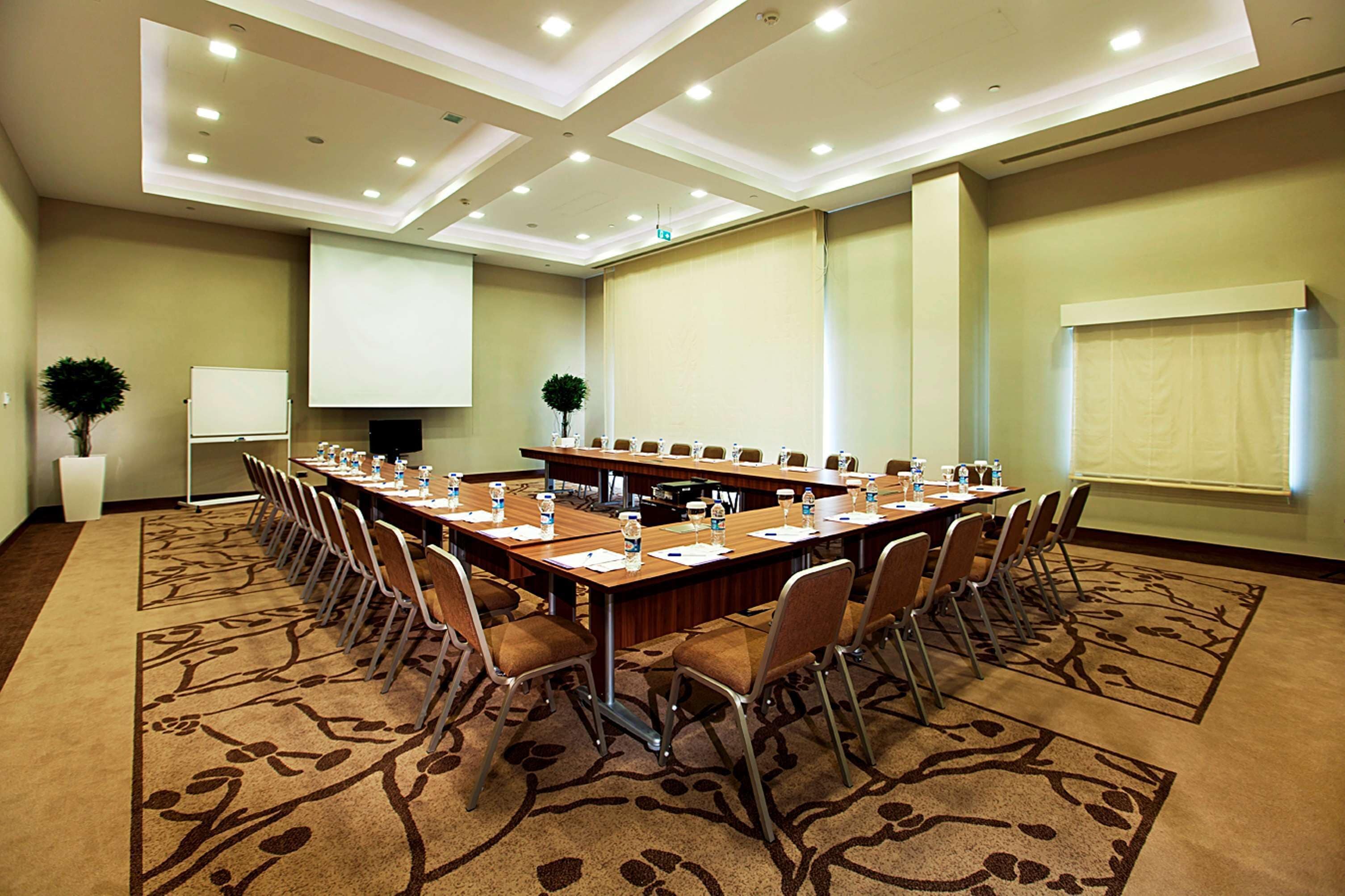 A conference room with a long table, chairs, a projector screen, and a whiteboard.