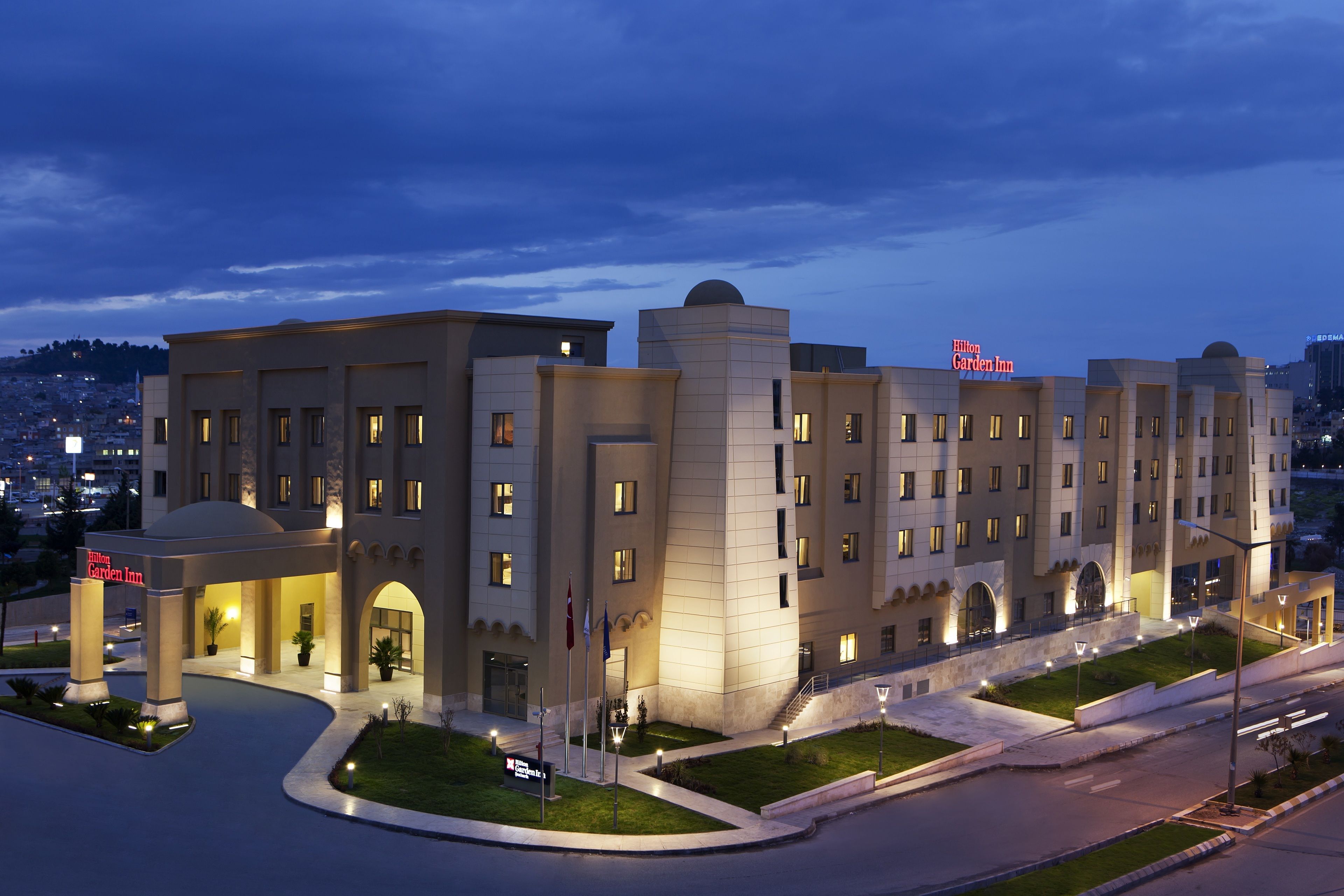 A multi-story hotel with a modern design, featuring a prominent entrance with a covered area and flagpoles.