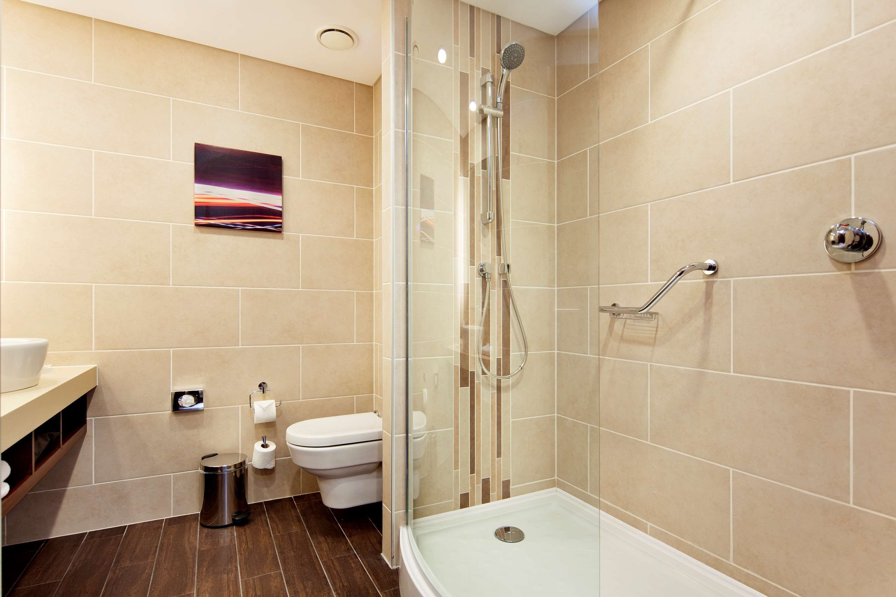 A modern bathroom with a glass-enclosed shower, a toilet, and a sink.