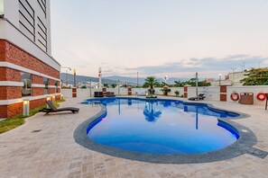 A swimming pool with lounge chairs and a brick building. - Hilton Garden Inn Tuxtla Gutierrez (Tuxtla Gutierrez)