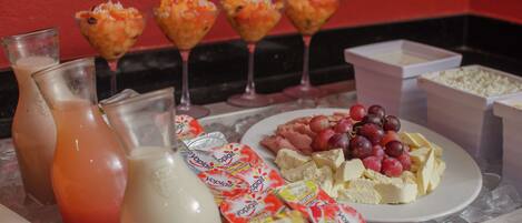 Una bandeja con diversos alimentos, incluyendo yogur, queso, uvas y una bebida.