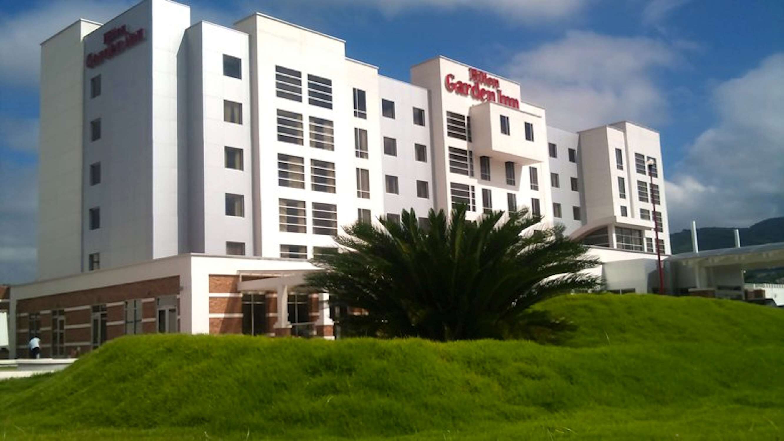 A modern hotel with a flat roof, multiple windows, and a sign reading "Garden Inn."