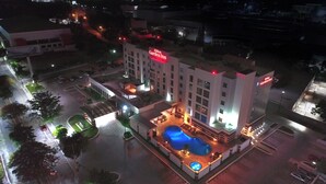 Un hotel con piscina, diversi piani e una facciata ben illuminata.