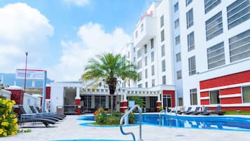 Ein Hotel mit mehreren Schwimmbecken, einer überdachten Außenbereich-Sitzgelegenheit und einem gut sichtbaren Hilton Garden Inn Schild.