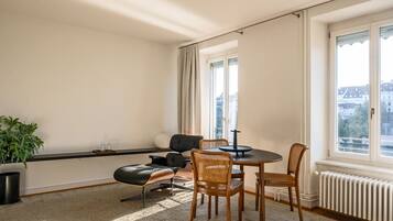 Ein modernes Zimmer mit Esstisch, Stühlen, einer Topfpflanze und einem Heizkörper.