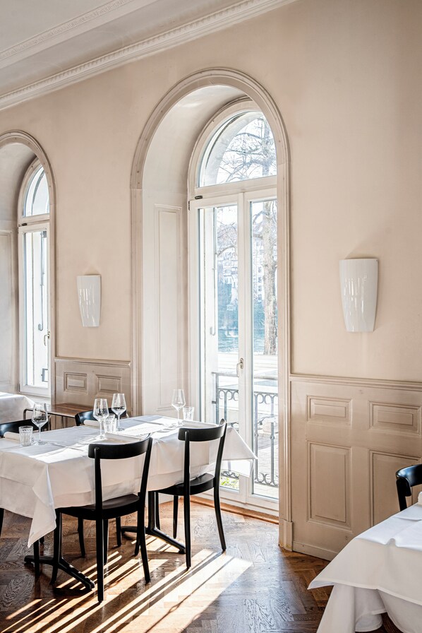 A dining area with a table set for four, large arched windows, and a view of the outside.