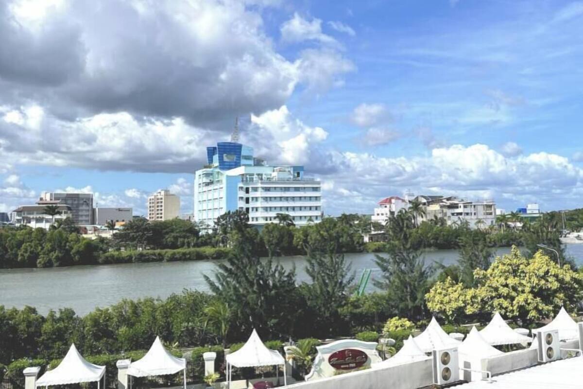 A cityscape with a prominent blue building, a body of water, and greenery.