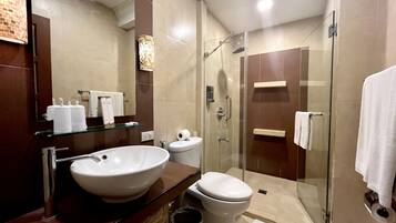 A modern bathroom with a large mirror, a sink, toilet, and a glass-enclosed shower area.
