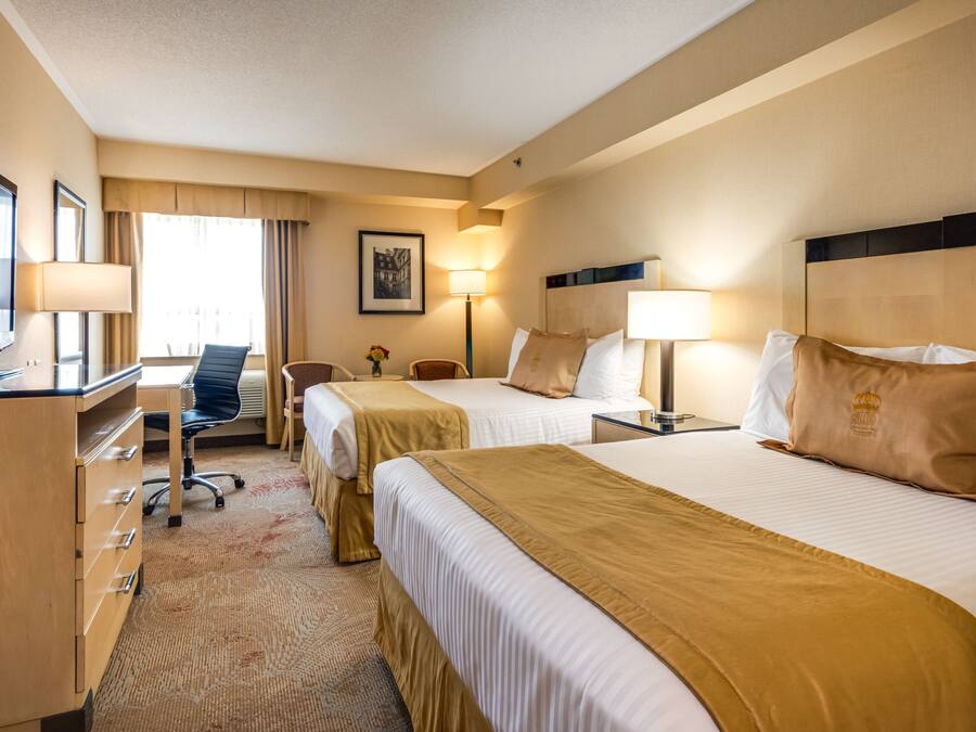 Een hotelkamer met twee bedden, een bureau met een televisie, een stoel en een bureaulamp.