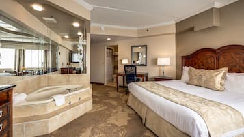 A hotel room with a large bed, a bathroom with a bathtub, a desk, and a chair.