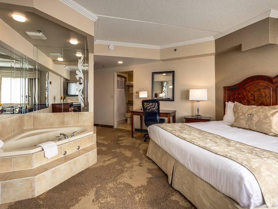 A hotel room with a large bed, a bathroom with a bathtub, a desk, and a chair.