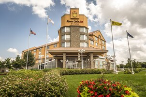 A hotel with a prominent sign, multiple flags, and a well-maintained garden.