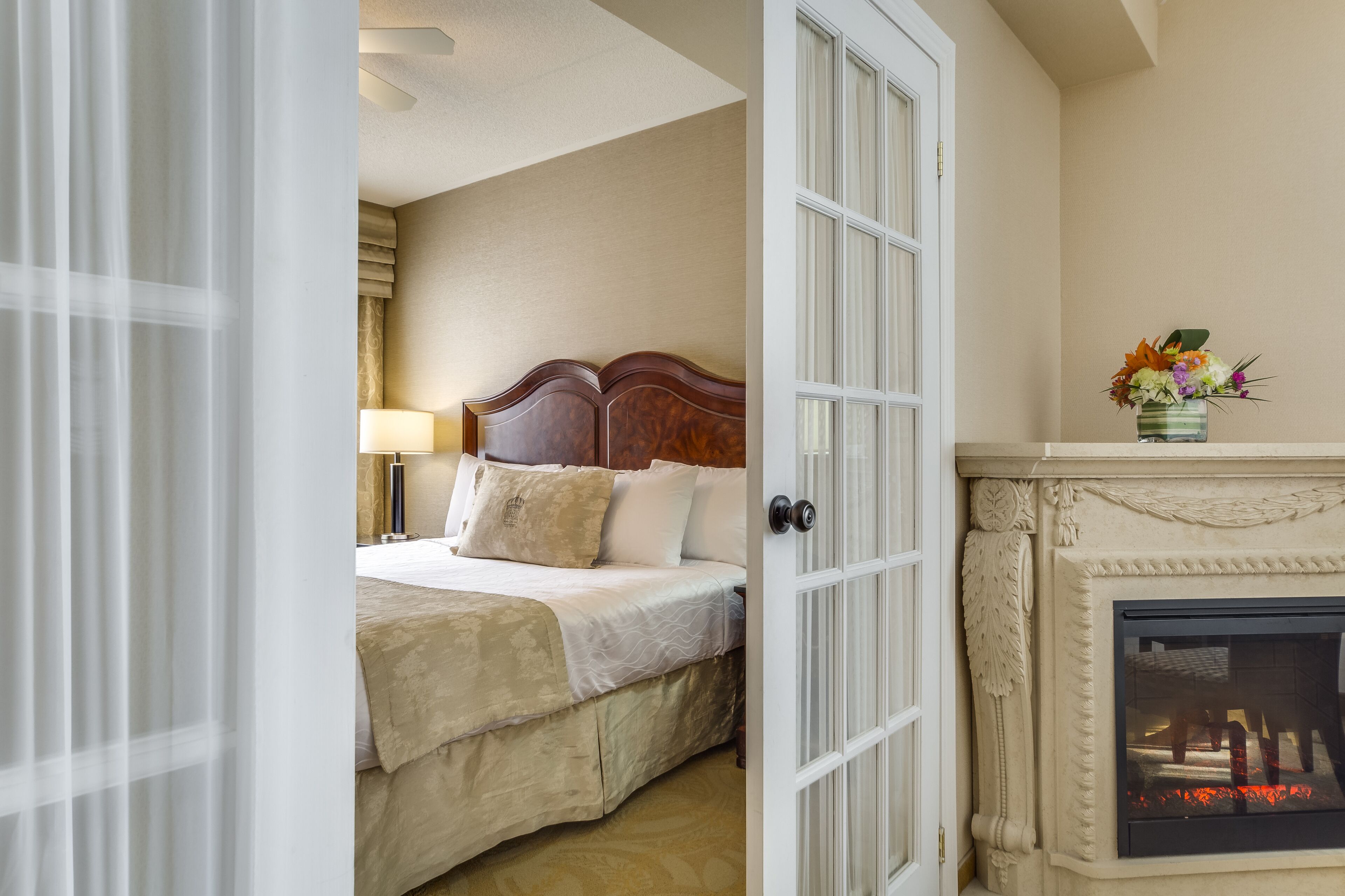 A hotel room with a bed, a fireplace, and a door leading to another room.