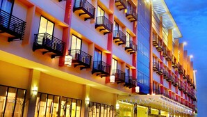 A multi-story hotel with balconies, large windows, and a well-lit entrance.