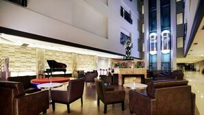 A spacious lobby with leather seating, a grand piano, and a modern chandelier.