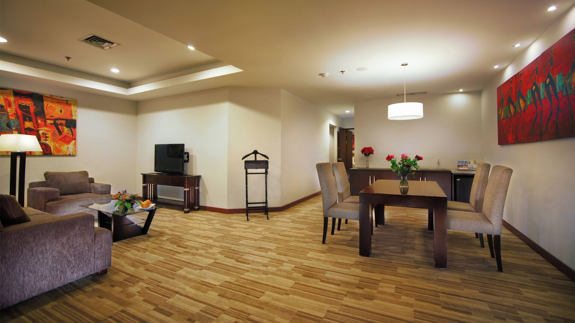 A modern living room with a sofa, TV, and dining area with chairs and a table.