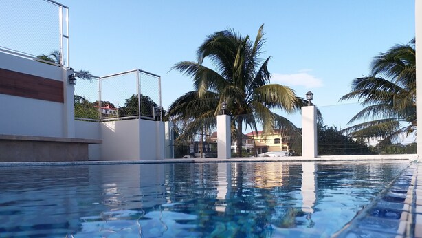 A clear swimming pool with a tiled edge, surrounded by a fence and palm trees. - Lee Boutique Hotel Tagaytay (Tagaytay)