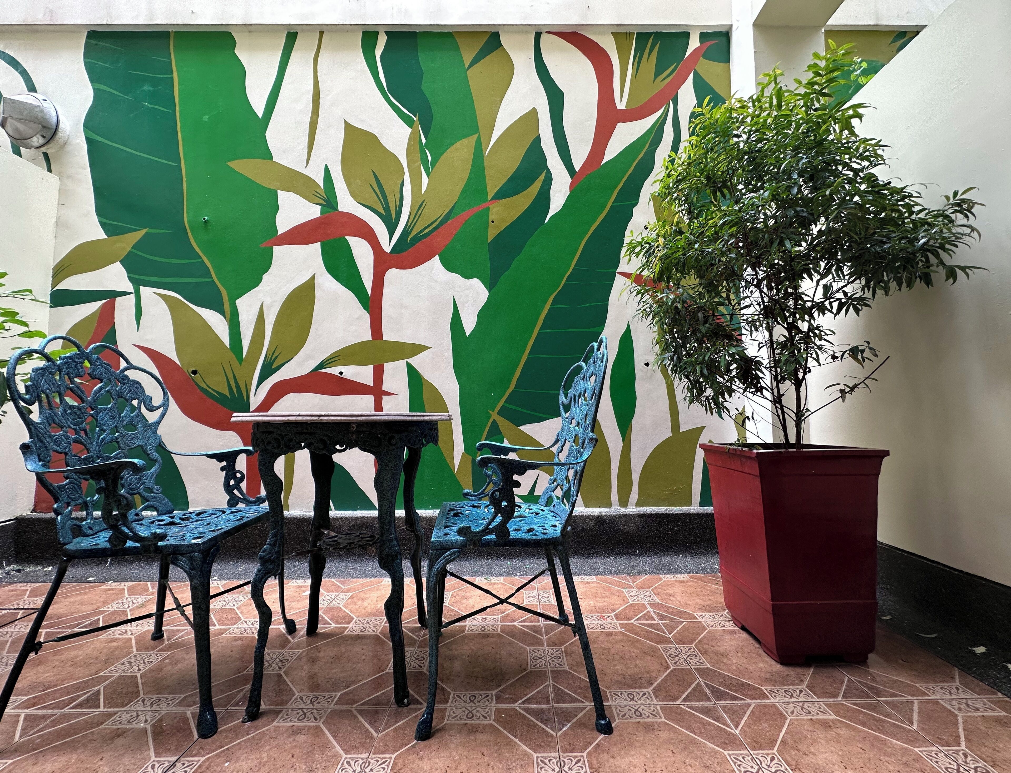Un'area patio con tavolo e sedie, una pianta in vaso e un murale.