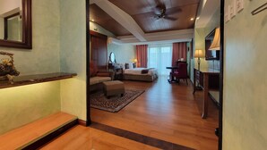A hotel room with a wooden floor, a bed, a desk, a chair, a TV, and a ceiling fan. - Lee Boutique Hotel Tagaytay (Tagaytay)