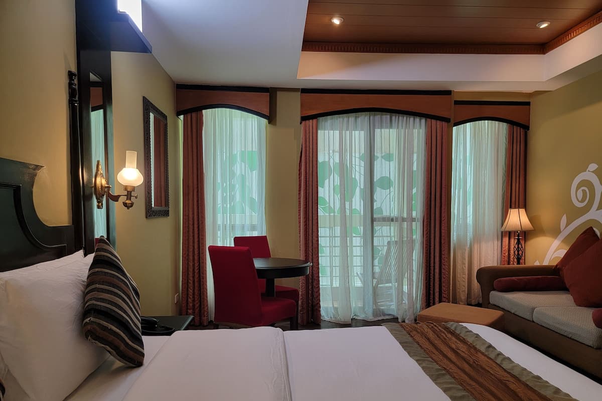 A hotel room with a bed, a desk, a chair, and a sofa.