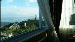A room with a large window offering a view of a distant landscape, including trees and a structure. - Lee Boutique Hotel Tagaytay (Tagaytay)