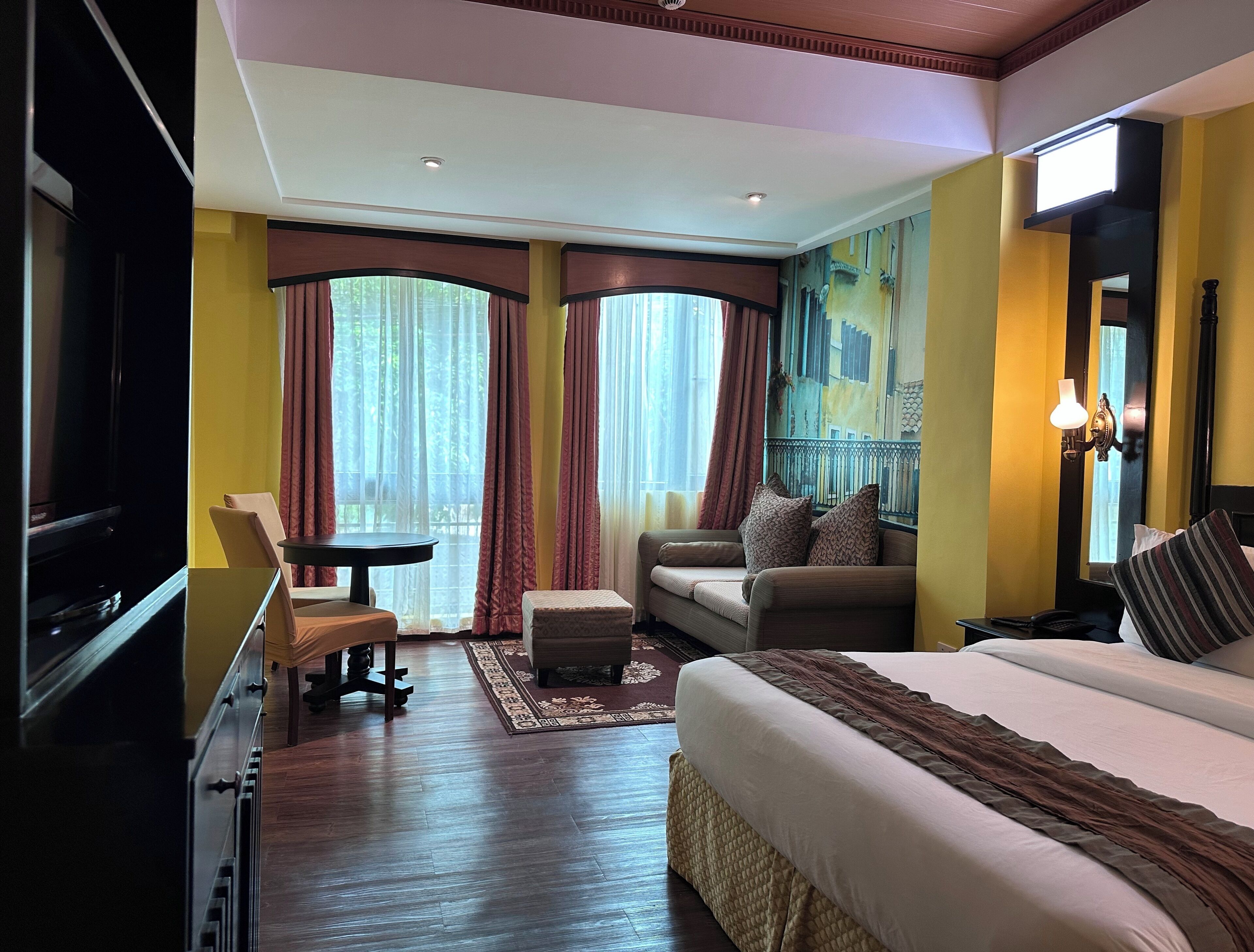 Ett hotellrum med en säng, en soffa, en stol, ett litet bord och en tv.