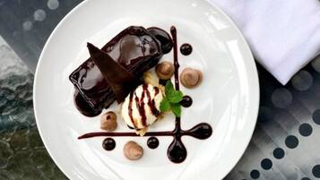 Un plato de postre con preparaciones cubiertas de chocolate y una bola de helado, decorado con hojas de menta.