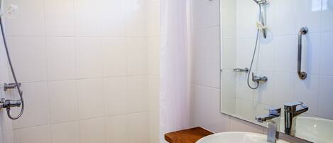 Un baño con ducha, lavamanos y espejo.