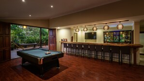 Een pooltafel in een ruimte met een bar en een groot scherm.