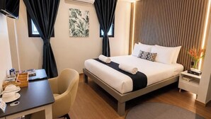 Een hotelkamer met een bed, bureau, stoel en een rond vloerkleed.