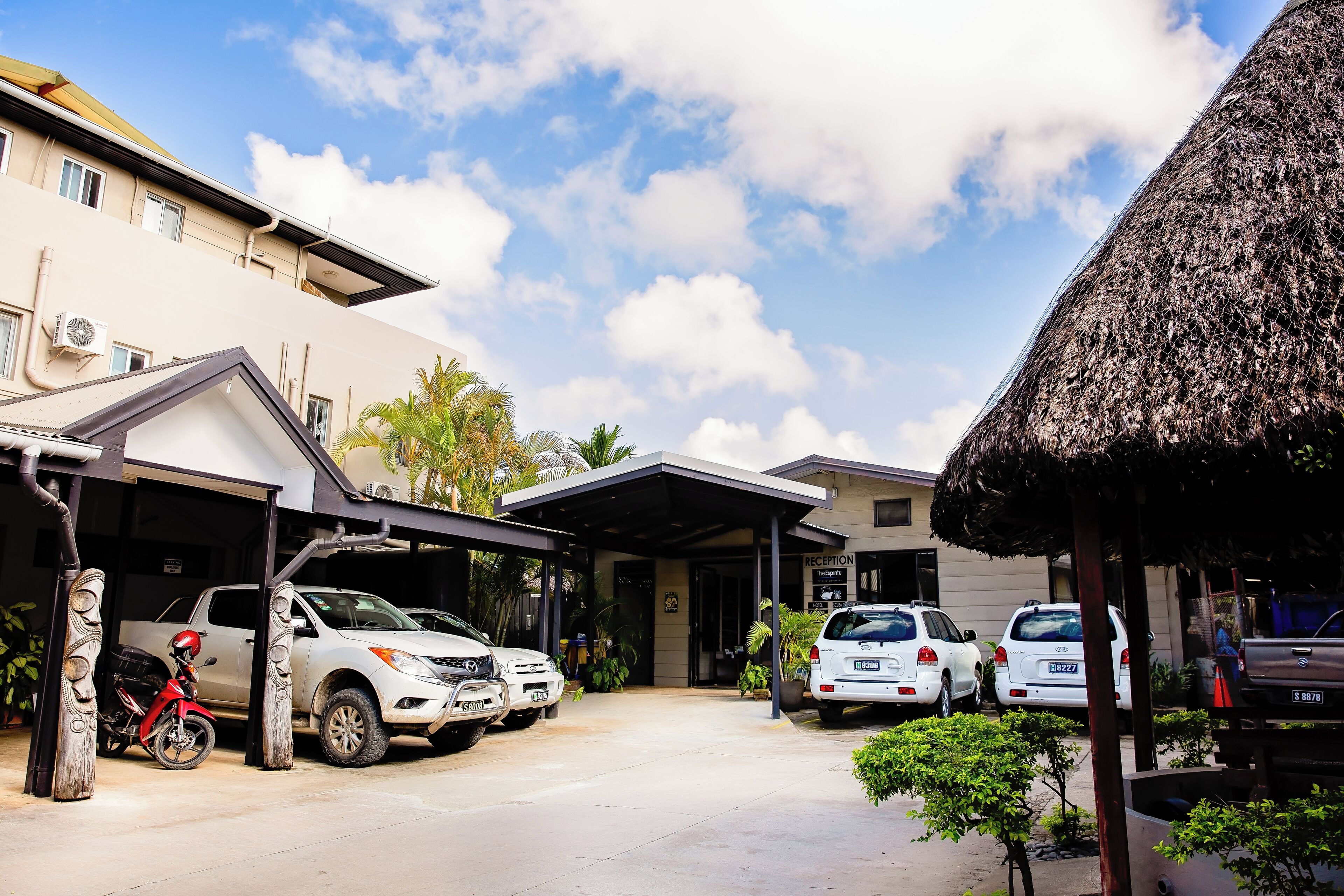 A building with a reception area, parked cars, and a covered parking space.