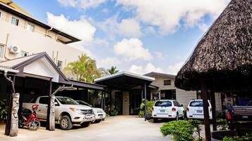 A building with a reception area, parked cars, and a covered parking space.
