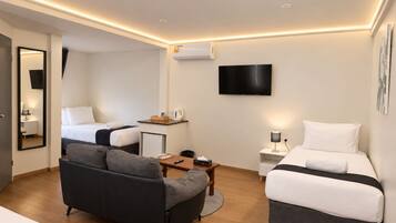 A modern hotel room with a sofa, a bed, a TV, and a small table.