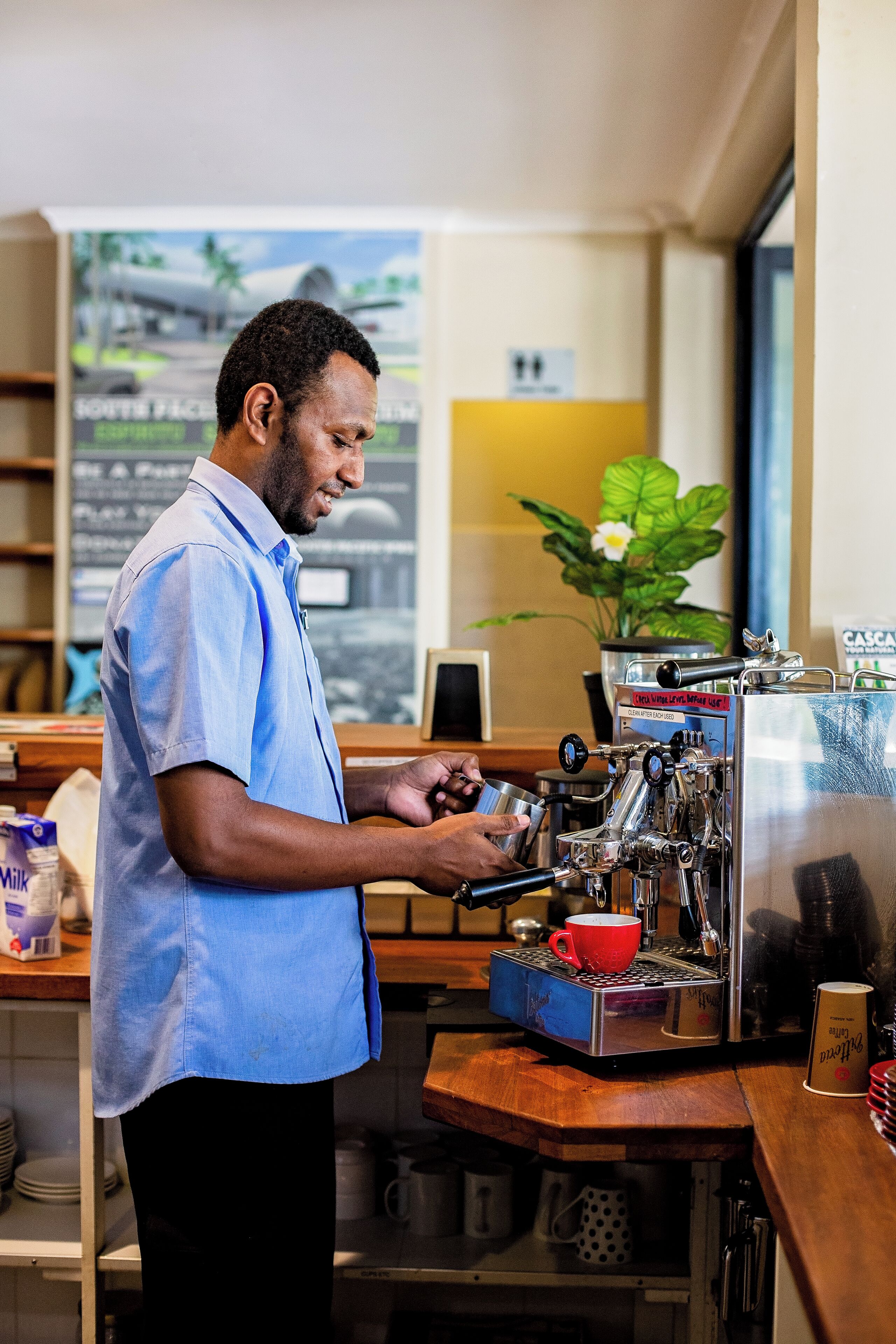 A person operating an espresso machine in a cafe setting.