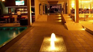 Una hall d'albergo con piscina, angolo bar e zona relax.