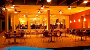 Un ristorante con diversi tavoli e sedie, ventilatori a soffitto e illuminazione calda.