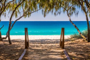 A beach path leading to the ocean with trees framing the view. - Island Beach Resort (Broadbeach)