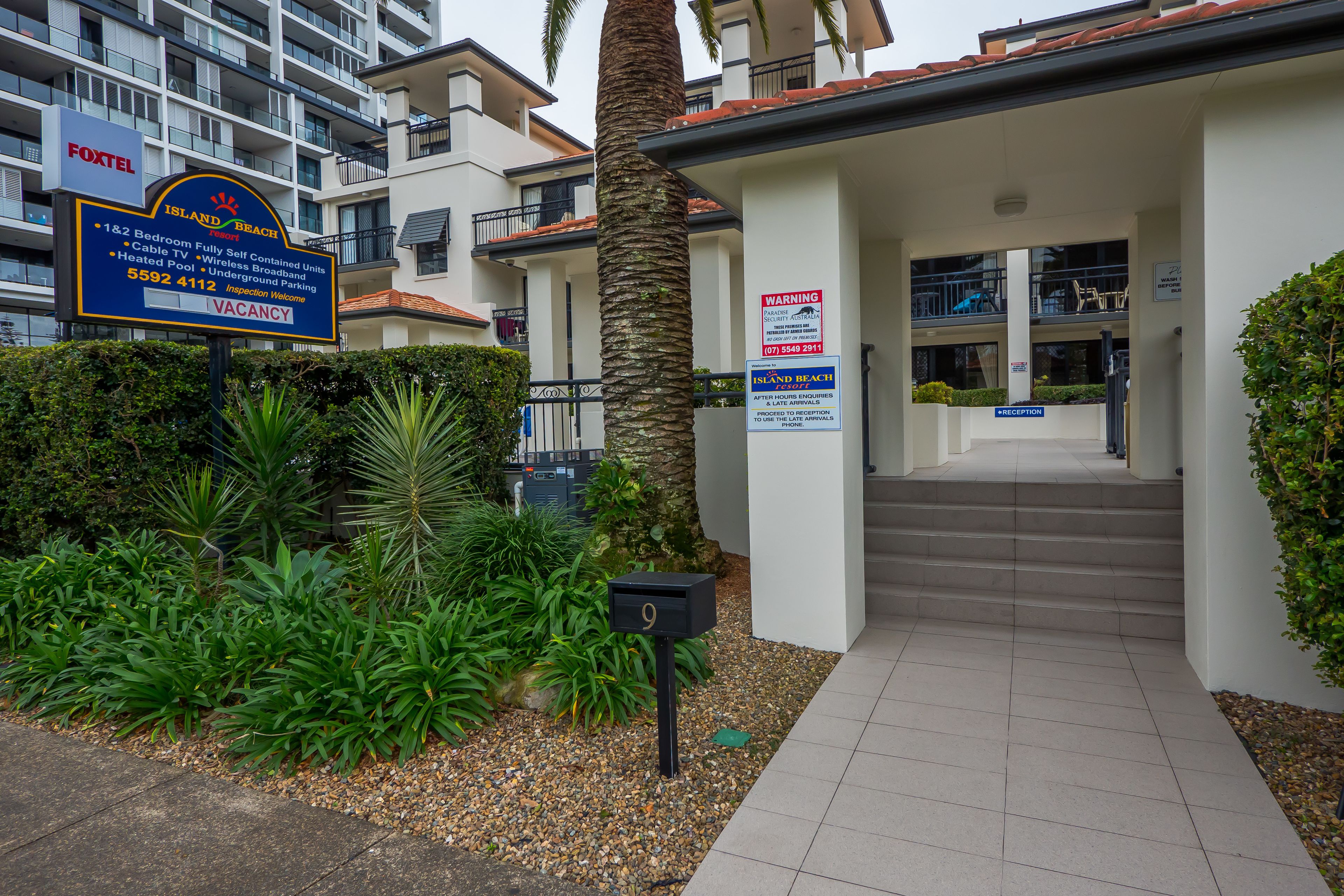 A hotel entrance with a sign indicating 1&2 bedroom units, fully self-contained, with cable, broadband, and heated pool.