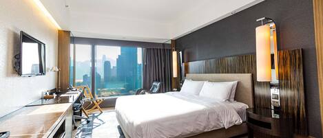 Una habitación de hotel moderna con una cama grande, un escritorio, una silla y vistas a la ciudad.