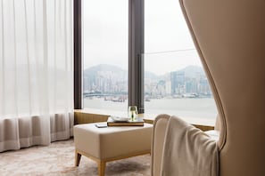 A hotel room with a large window, a chair, a small table with a book and a glass of water, and a carpeted floor. - Hotel ICON (Kowloon)