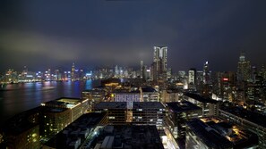 A nighttime cityscape with a river, high-rise buildings, and a prominent skyscraper.