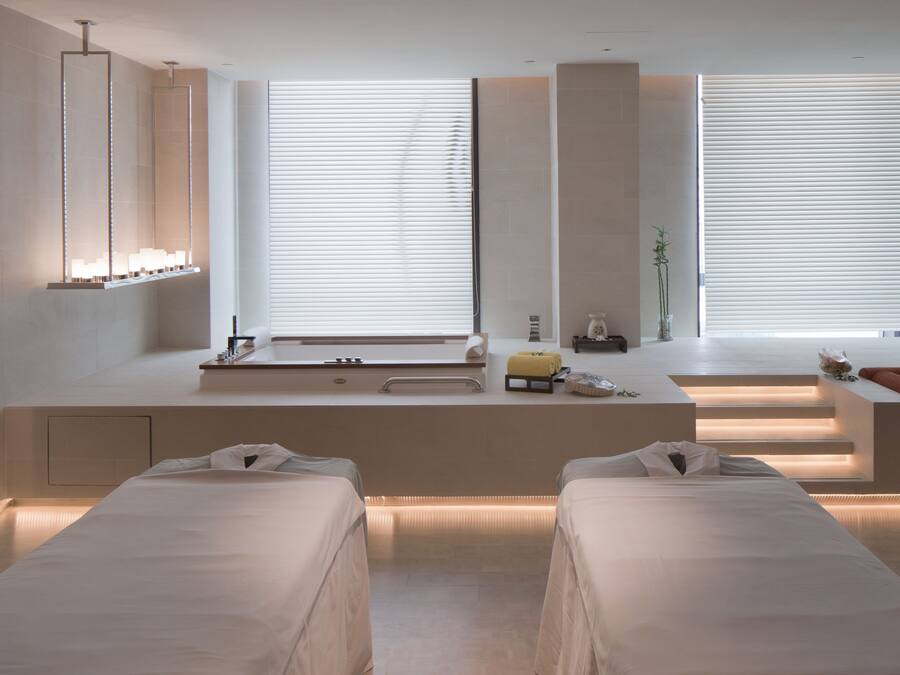 Een moderne spa-ruimte met een groot raam, een badkuip en twee bedden.