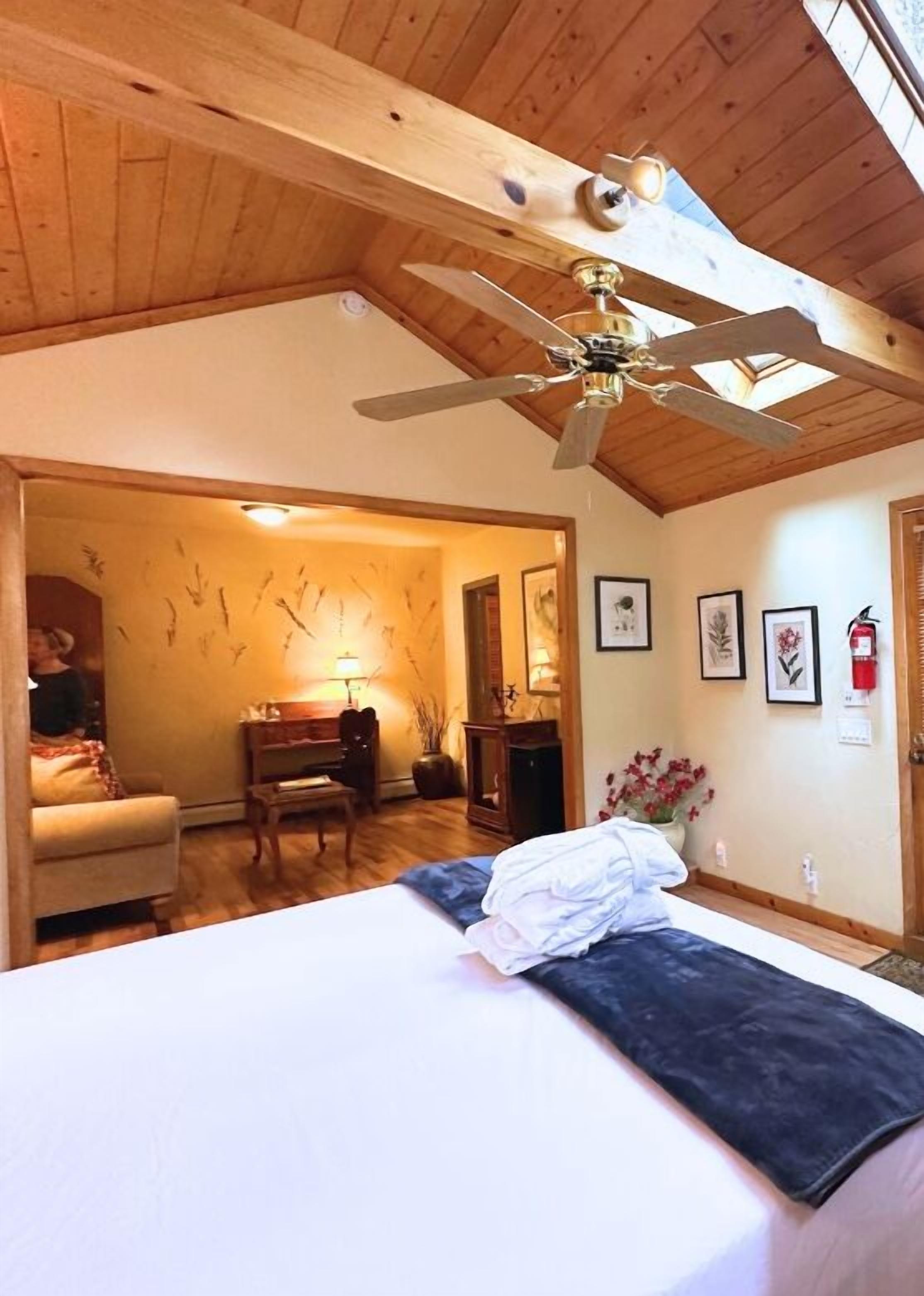 A bedroom with a bed, a desk, a chair, and a ceiling fan.